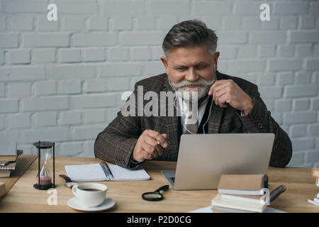 happy senior writer working with laptop Stock Photo