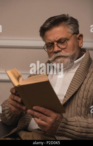 concentrated senior man in eyeglasses reading book Stock Photo