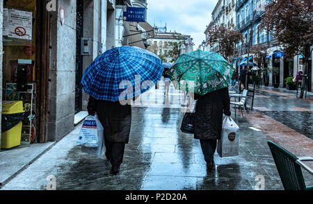 Rear view of two people walking side by side, using umbrellas on a rainy morning, Madrid, Spain. Stock Photo