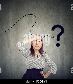 Young woman thinking hard trying to remember has a question Stock Photo