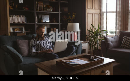 Man sitting on sofa using his laptop Stock Photo