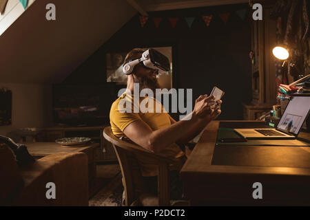 Man wearing virtual reality headset  using his mobile phone Stock Photo