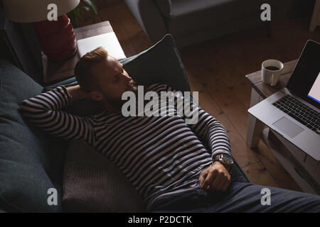 man lying on sofa watching laptop Stock Photo