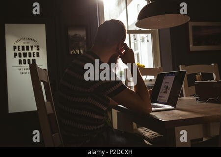 Man sitting on chair using his laptop Stock Photo