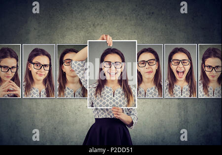 Girl holds and changing her face portraits with different expressions. Woman expressing different emotions Stock Photo