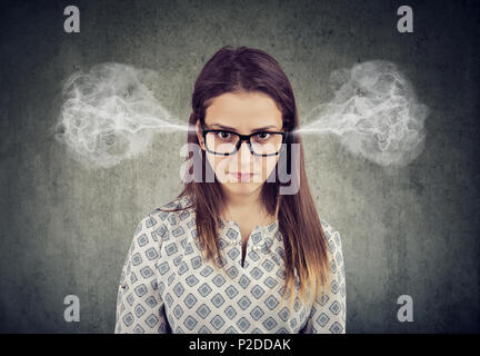 Closeup portrait of angry woman, blowing steam coming out of ears isolated on gray background. Negative human emotions feelings Stock Photo