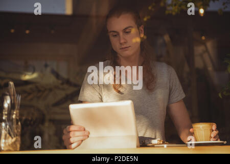 Man using digital tablet while having coffee Stock Photo