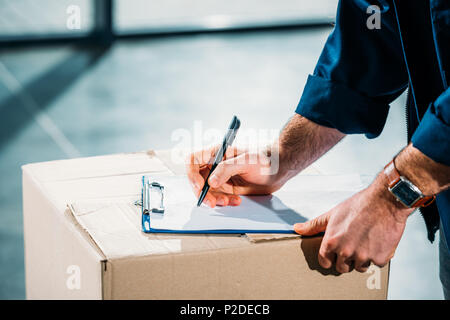 Courier filling cargo declaration on cardboard package Stock Photo