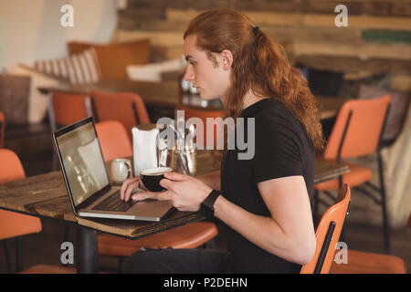 Man using laptop while having coffee Stock Photo