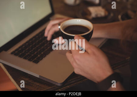 Close-up of man using laptop while having coffee Stock Photo