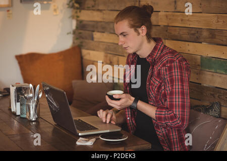Man using laptop while having coffee Stock Photo