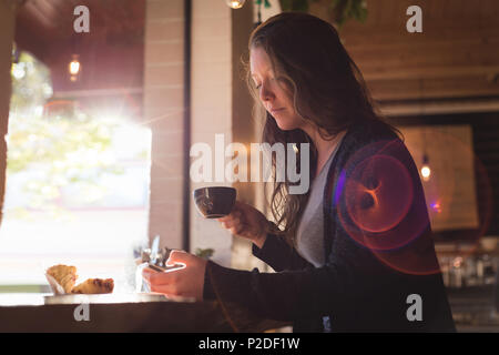 Woman using mobile phone while having coffee Stock Photo
