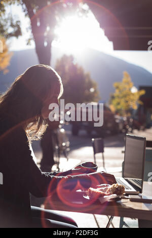 Woman using laptop while having coffee Stock Photo