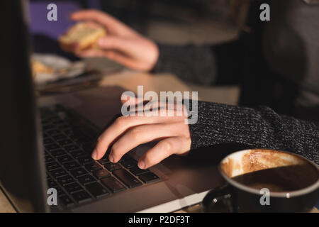 Woman using laptop while having coffee Stock Photo