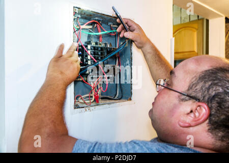 Miami Beach Florida,Hispanic,immigrant immigrants,man men male,electrician,working,electrical panel,breaker box,circuit breakers,wires,job,repair,FL17 Stock Photo