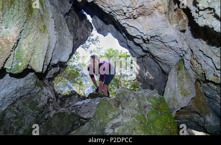 Young woman looking into cave in which food has been stored, Selvaggio Blu, Sardinia, Italy, Europe Stock Photo