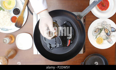 Olive oil poured into the frying pan from the bottle Stock Photo