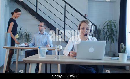 Beautiful call center agent having phone call and browsing the internet on her computer Stock Photo