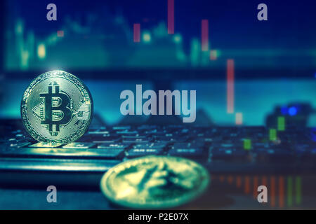 Close up of golden bitcoins on computer keyboard and screen, dark themed Stock Photo