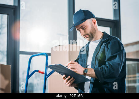 Loader man filling cargo declaration by stacks boxes Stock Photo