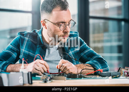 Repairman testing circuit board and checking multimeter measurements Stock Photo