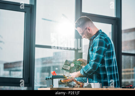 Male engineer looking at circuit board Stock Photo