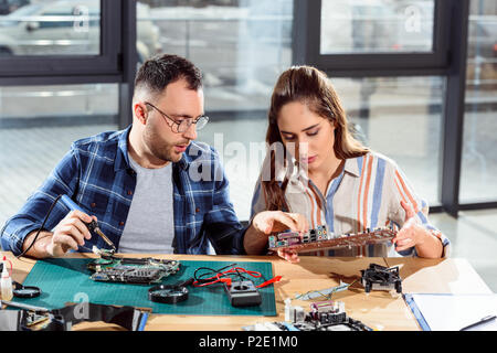 Man assisting woman in circuit board repair Stock Photo