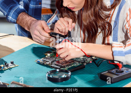 Man helping woman testing elements of circuit board Stock Photo