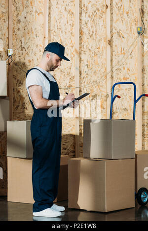 Loader man filling cargo declaration by delivery cart Stock Photo