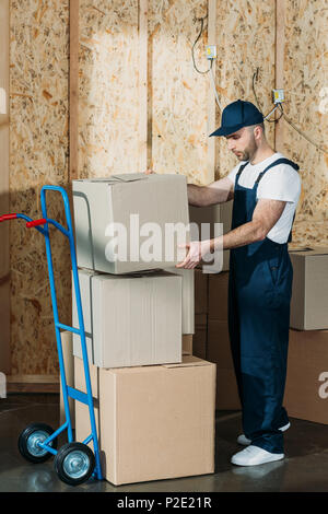Loader man stacking cardboard boxes on hand truck Stock Photo - Alamy