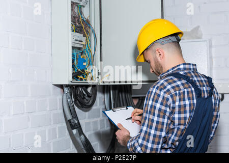 Professional electrician inspecting wires in electrical box Stock Photo