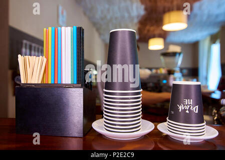 Piles of disposable paper cups, multicolored straws and wooden sticks on the counter. Stock Photo