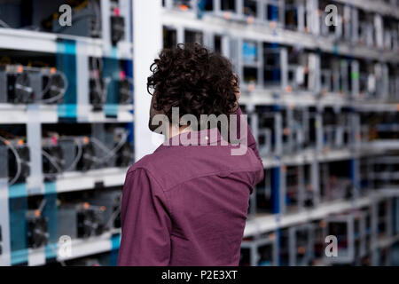 rear view of computer engineer looking at cryptocurrency mining farm Stock Photo