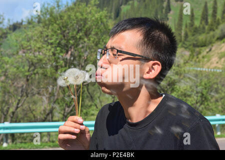 Chinese guy blowing seeds to the wind, Xinjiang, China Stock Photo