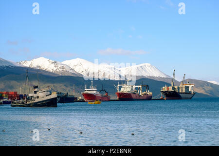 The Saint-Christopher, an old boat, lies in the bay of Ushuaia. Behind that are a few container ships who show some small harbor activity. Stock Photo