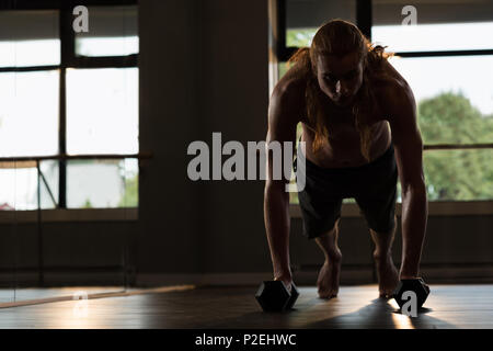 Man doing push-ups with dumbbells Stock Photo
