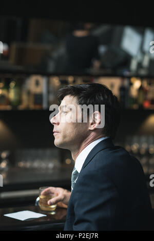 Thoughtful businessman having glass of whisky Stock Photo