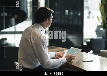Thoughtful businessman using digital tablet Stock Photo