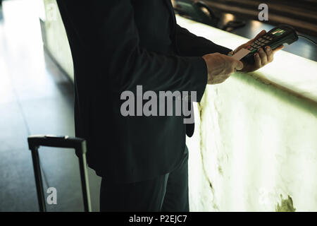 Businessman swiping his card on payment terminal machine Stock Photo