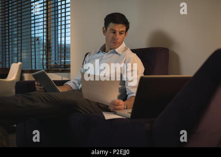 Business man verifying documents while using digital tablet Stock Photo