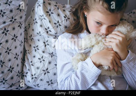 Girl holding teddy bear on bed Stock Photo