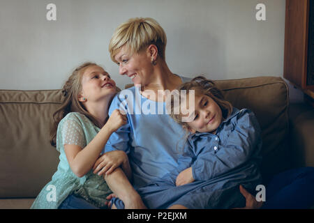 Mother and daughters relaxing on sofa Stock Photo