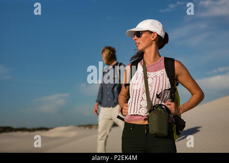 Couple with backpack standing on sand Stock Photo