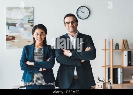 Businessman and businesswoman smiling and standing in modern office Stock Photo