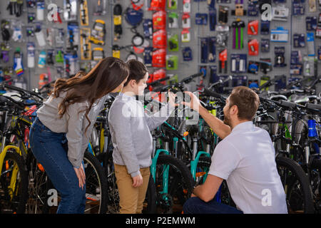 manager helping to choose bicycle to happy mother and son in bike shop