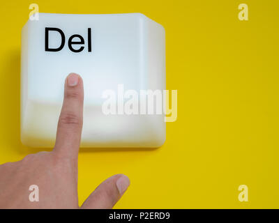 Finger is Pressing Big Delete Computer Key Button Light Box Isolated on Yellow Background with Space. Eraser Concept. Stock Photo