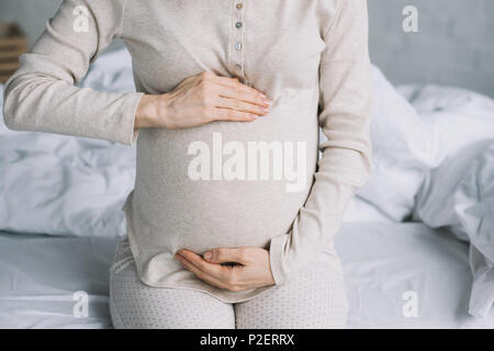 cropped image of pregnant woman touching belly in bedroom Stock Photo