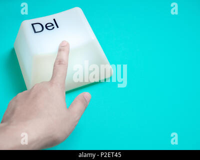 Finger is Pressing Big Delete Computer Key Button Light Box Isolated on Aqua Blue or Green Background with Space. Eraser Concept. Stock Photo