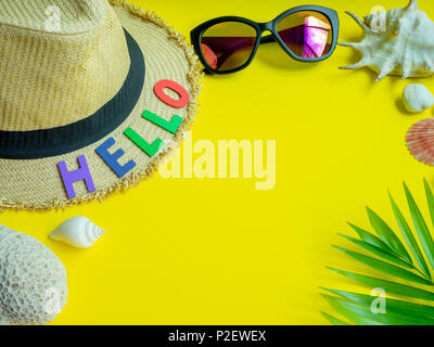 Flat Lay Beach Accessories, Hat, Sunglasses with Hello Colourful Text, Beach Seashells, Coral, Beach Pebbles and Coconut Palm Leaf on Lemon Yellow Bac Stock Photo