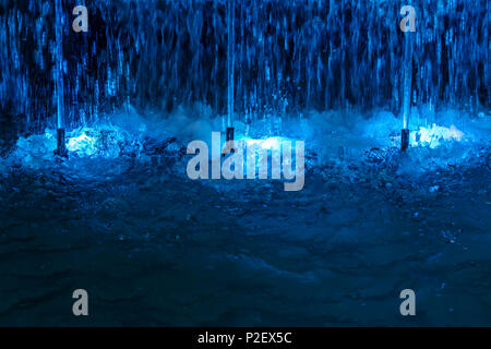 fountain with blue illuminations at night. colored water jets closeup view Stock Photo